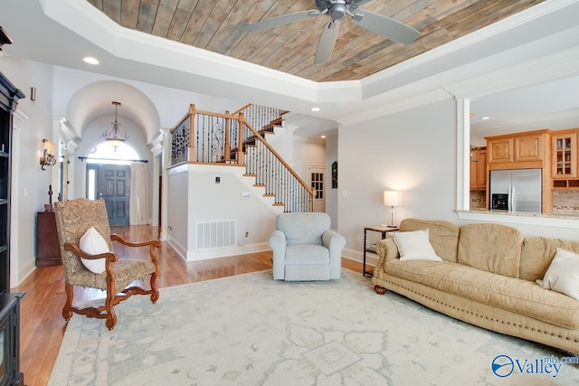 living room with visible vents, stairway, arched walkways, wooden ceiling, and a raised ceiling