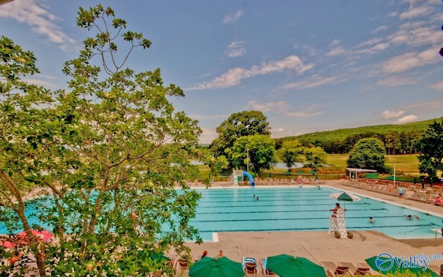 community pool with a patio and a water slide