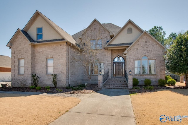 view of front of house with brick siding, stucco siding, and a shingled roof