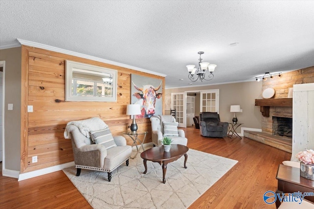 living room featuring ornamental molding, a stone fireplace, a textured ceiling, wooden walls, and hardwood / wood-style flooring