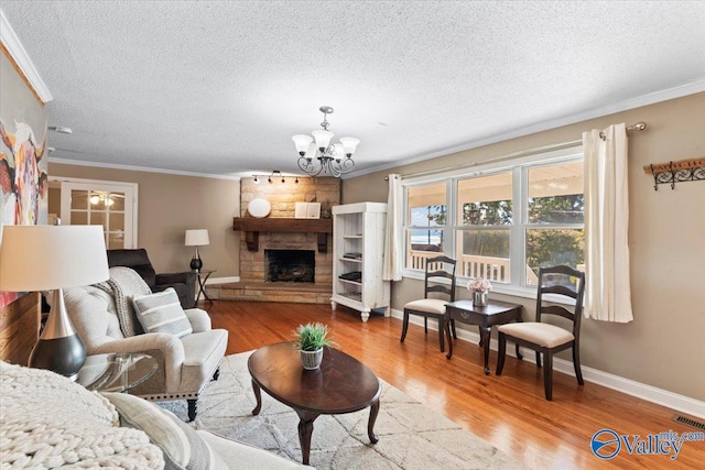 living room with a stone fireplace, an inviting chandelier, crown molding, and light hardwood / wood-style floors