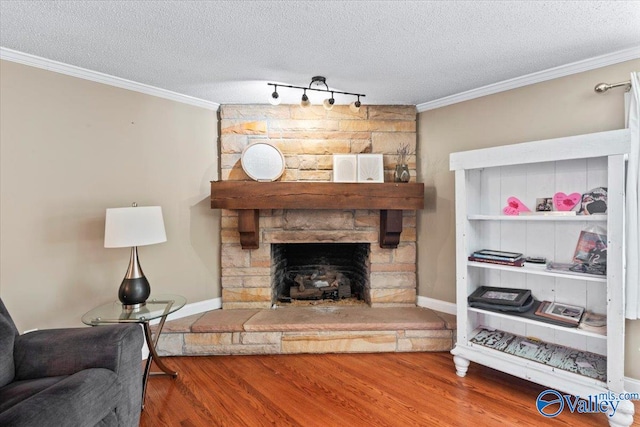 living room with ornamental molding, a textured ceiling, hardwood / wood-style flooring, and a fireplace