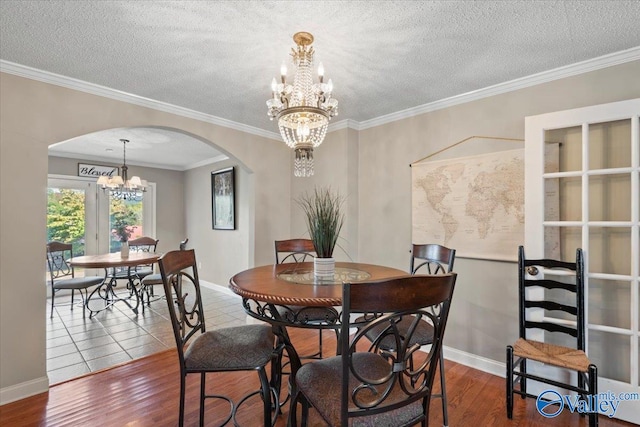 dining room featuring a notable chandelier, a textured ceiling, ornamental molding, and hardwood / wood-style flooring