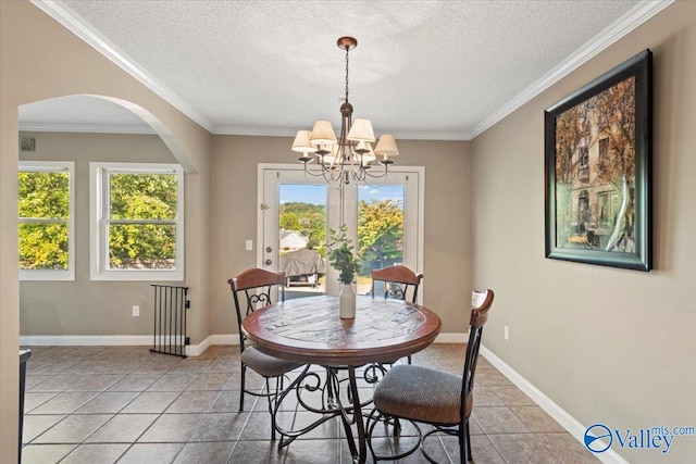 tiled dining space featuring an inviting chandelier, ornamental molding, and a textured ceiling