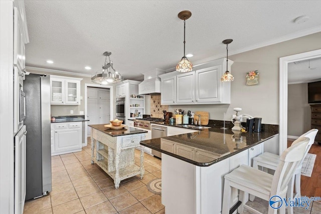 kitchen featuring white cabinets, kitchen peninsula, a kitchen bar, appliances with stainless steel finishes, and decorative light fixtures