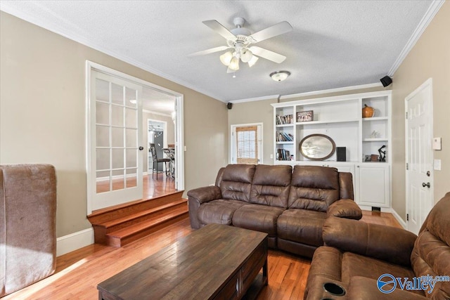 living room with light hardwood / wood-style flooring, ceiling fan, crown molding, and a textured ceiling