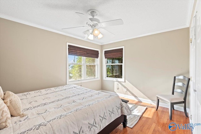 bedroom featuring a textured ceiling, ceiling fan, hardwood / wood-style floors, and crown molding