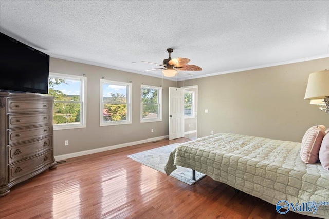 bedroom with a textured ceiling, crown molding, ceiling fan, and hardwood / wood-style flooring