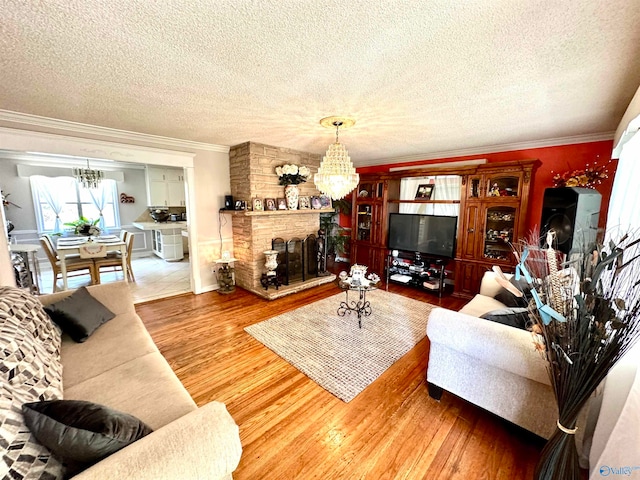 living room with a fireplace, light hardwood / wood-style flooring, a textured ceiling, and a chandelier