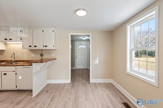 kitchen featuring white cabinetry, sink, white dishwasher, and light wood-type flooring