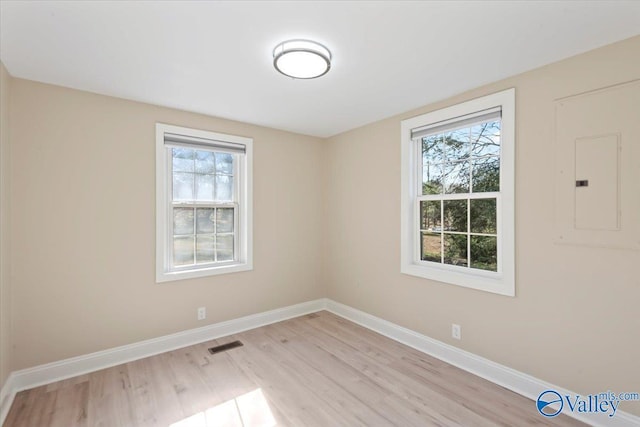 empty room with electric panel and light hardwood / wood-style flooring