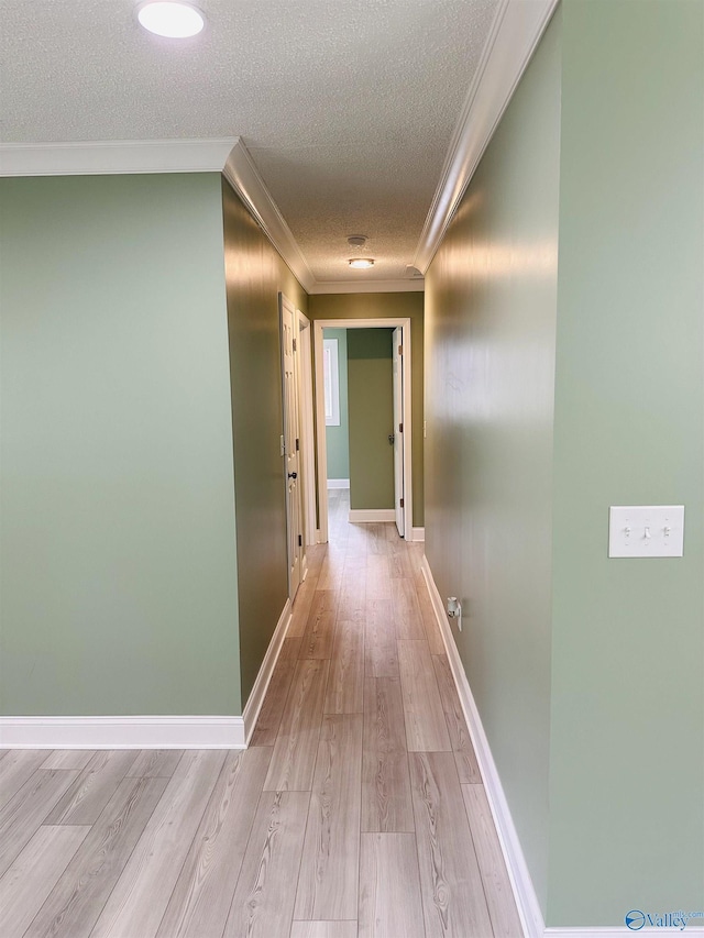 hallway with crown molding, light hardwood / wood-style flooring, and a textured ceiling