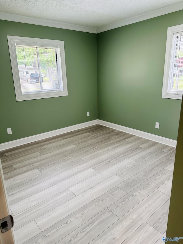 spare room featuring ornamental molding, a textured ceiling, and light hardwood / wood-style flooring