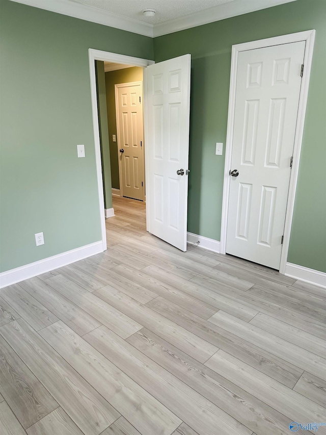 unfurnished bedroom with ornamental molding and light hardwood / wood-style floors