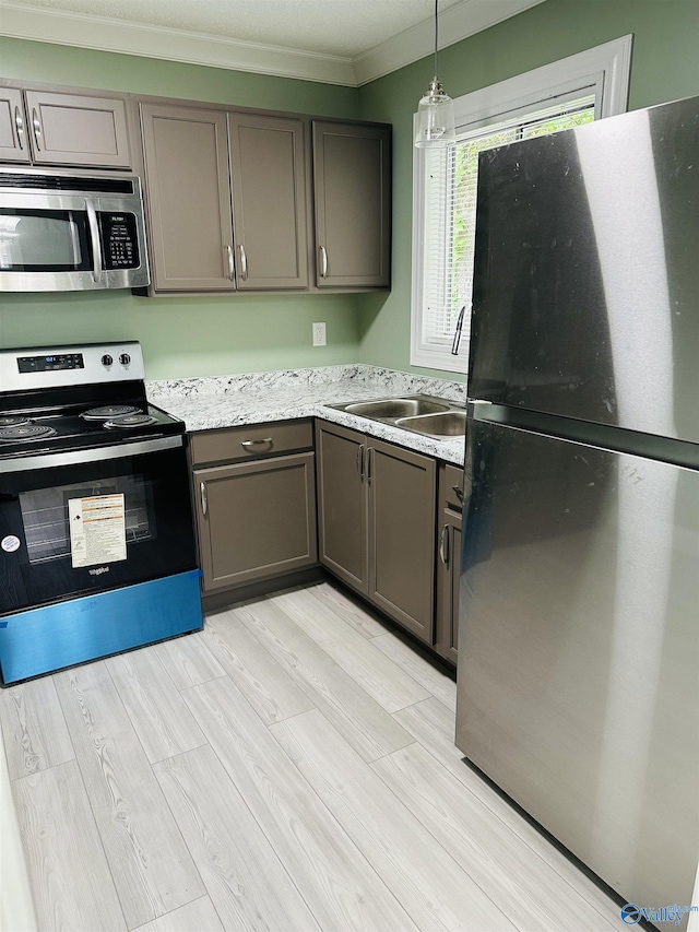 kitchen with light wood-type flooring, ornamental molding, pendant lighting, stainless steel appliances, and light stone countertops