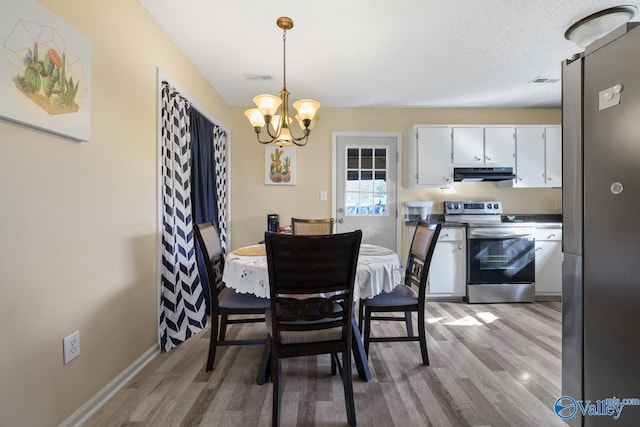 dining room featuring light hardwood / wood-style floors, a textured ceiling, and a notable chandelier