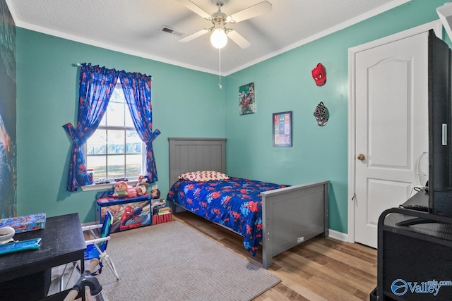 bedroom with a textured ceiling, hardwood / wood-style flooring, ceiling fan, and crown molding