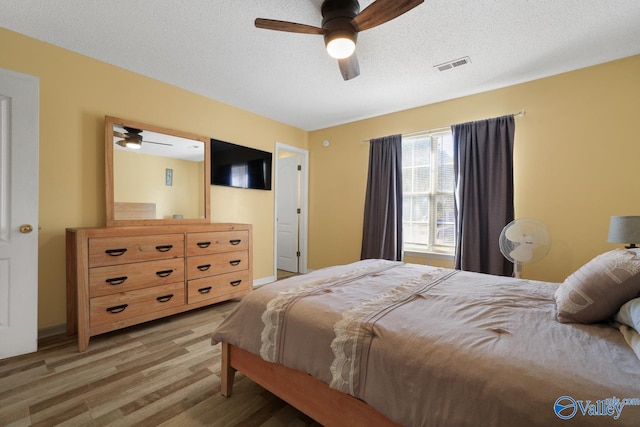 bedroom featuring ceiling fan, hardwood / wood-style floors, and a textured ceiling