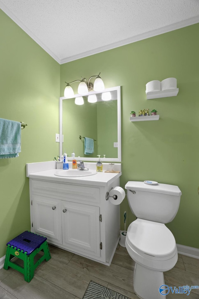 bathroom with ornamental molding, vanity, a textured ceiling, wood-type flooring, and toilet