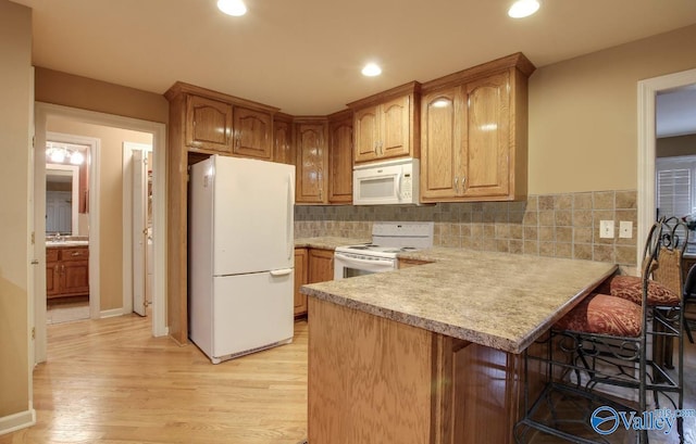 2220 Jefferson St, Courtland, AL 35618 - kitchen featuring white appliances, light countertops, a kitchen bar, a peninsula, and light wood-style floors