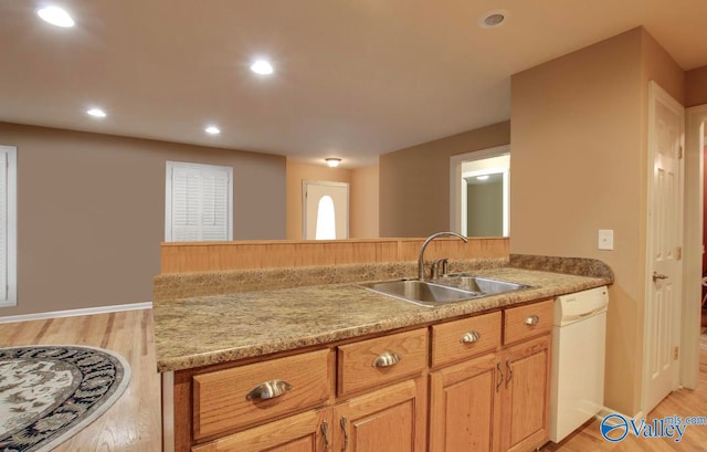 kitchen with light stone counters, dishwasher, light wood-type flooring, and sink