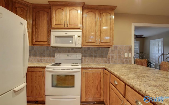 kitchen featuring light stone countertops, tasteful backsplash, and white appliances