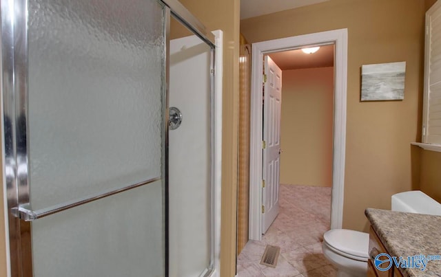 bathroom featuring vanity, a shower with shower door, and toilet