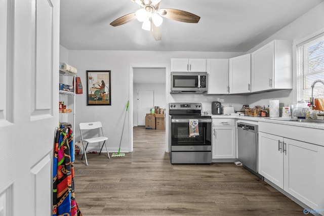 kitchen with white cabinets, a sink, ceiling fan, stainless steel appliances, and wood finished floors
