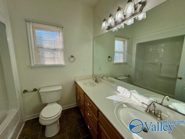17215 Eunice Ln, Athens, AL 35613 - full bathroom featuring toilet, double vanity, tile patterned flooring, baseboards, and  shower combination