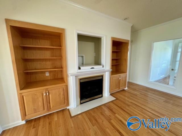 unfurnished living room with ornamental molding, built in shelves, and light hardwood / wood-style flooring