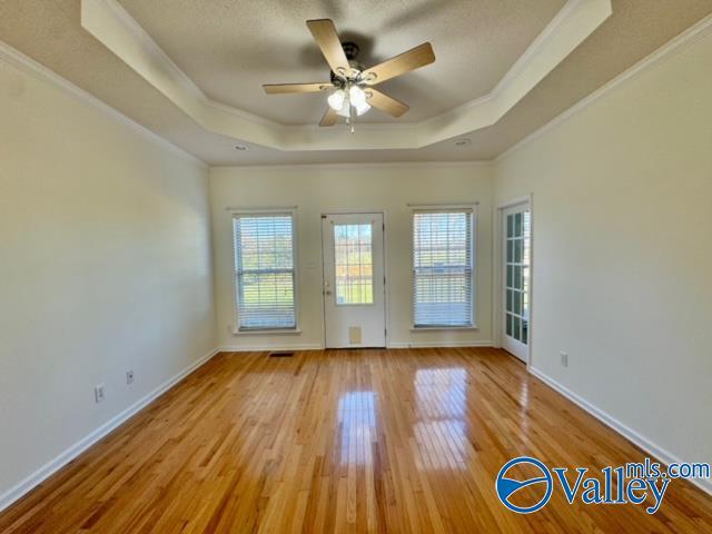 17215 Eunice Ln, Athens, AL 35613 - empty room featuring a tray ceiling, healthy amount of natural light, crown molding, ceiling fan, and light wood-style floors