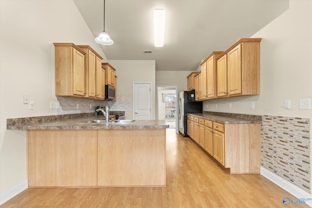 kitchen with stainless steel appliances, light brown cabinetry, sink, and hanging light fixtures