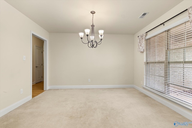 empty room with carpet floors and a chandelier