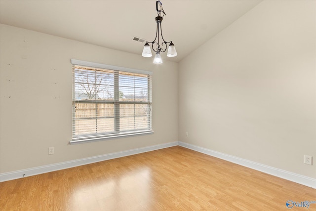 unfurnished dining area with an inviting chandelier, vaulted ceiling, and light hardwood / wood-style floors