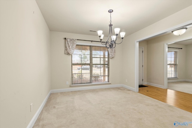 carpeted spare room featuring a notable chandelier