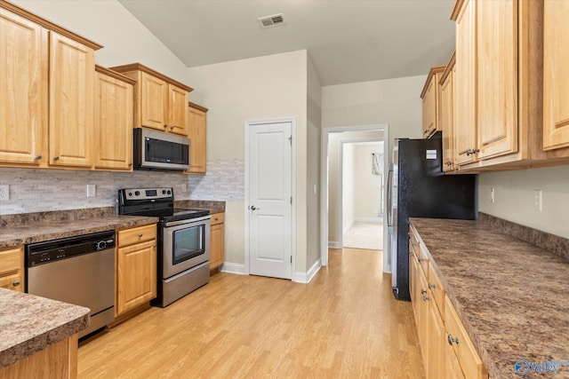 kitchen with appliances with stainless steel finishes, light brown cabinetry, backsplash, and light hardwood / wood-style floors