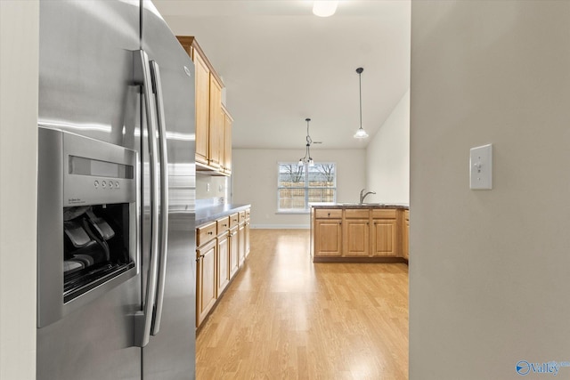 kitchen with sink, stainless steel fridge, hanging light fixtures, light brown cabinets, and light wood-type flooring