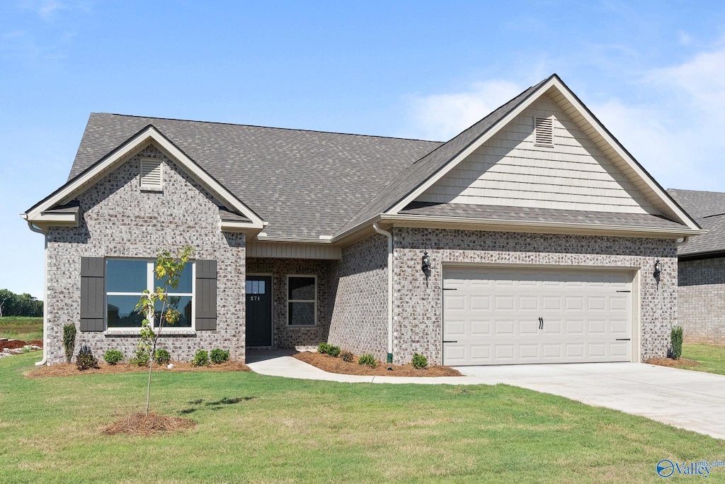 271 Shubert Dr, Hazel Green, AL 35750 - view of front of house with a front lawn, concrete driveway, an attached garage, a shingled roof, and brick siding