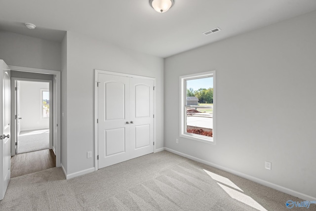 unfurnished bedroom with light carpet and a closet