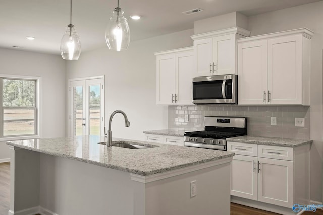 kitchen featuring stainless steel appliances, white cabinetry, sink, wood-type flooring, and a kitchen island with sink