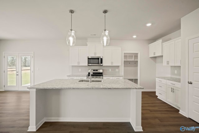 kitchen featuring a kitchen island with sink, stainless steel appliances, sink, hanging light fixtures, and white cabinets