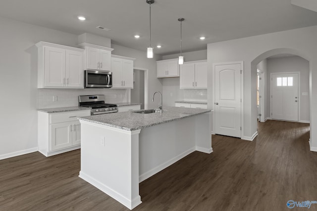 kitchen featuring a kitchen island with sink, light stone counters, white cabinetry, and stainless steel appliances