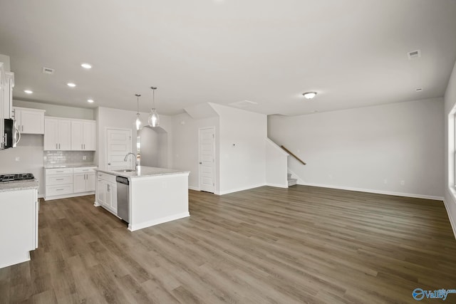 kitchen with dark hardwood / wood-style floors, decorative light fixtures, a center island with sink, sink, and white cabinetry