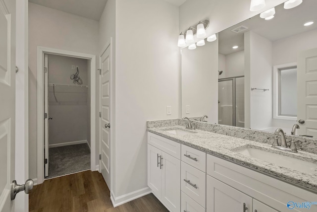 bathroom featuring a shower with shower door, hardwood / wood-style flooring, and vanity