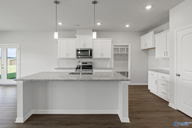 kitchen with white cabinets, stainless steel appliances, dark hardwood / wood-style floors, a center island with sink, and tasteful backsplash