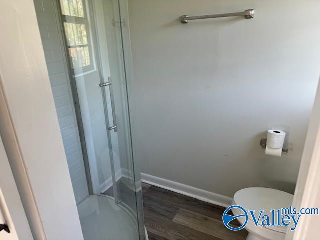 bathroom featuring walk in shower, hardwood / wood-style floors, and toilet