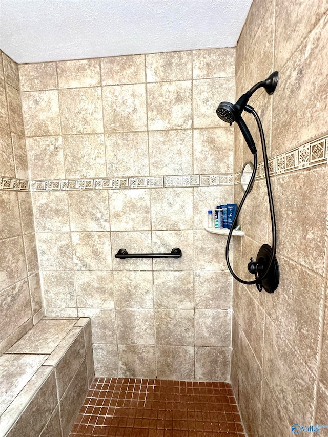 bathroom with a textured ceiling and tiled shower