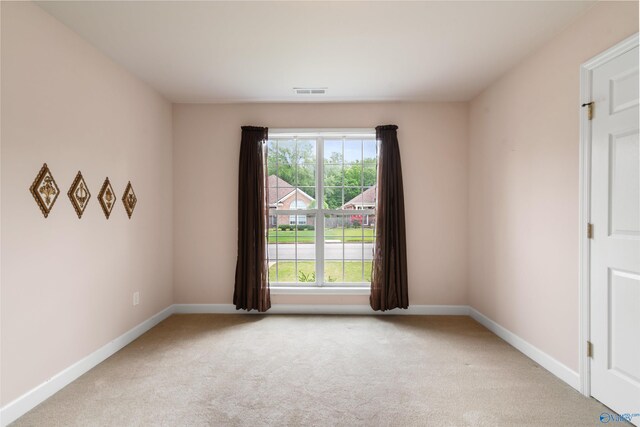 unfurnished room featuring light carpet and baseboards