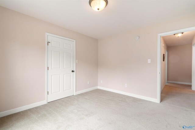 empty room featuring light carpet and baseboards