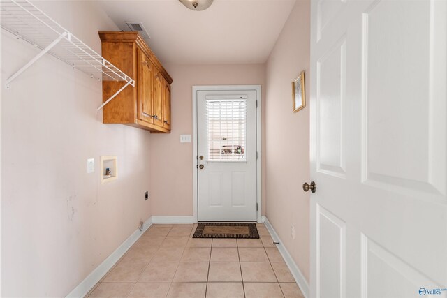 washroom featuring washer hookup, electric dryer hookup, light tile patterned floors, baseboards, and cabinet space